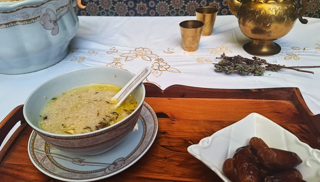 Close up of creamy Moroccan Barley Soup (Hassoua) in a rustic bowl, drizzled with extra virgin olive oil.