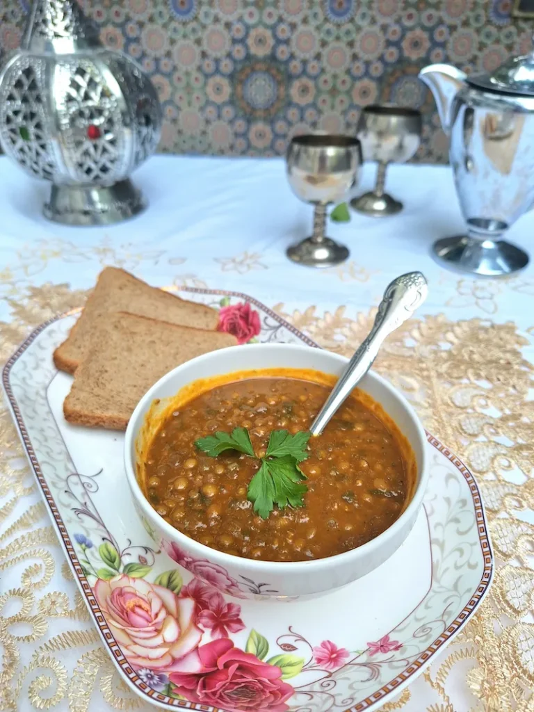 A steaming bowl of One-Pot Moroccan Lentils served with two slices of crusty bread on a cute decorative tray, ready to enjoy.