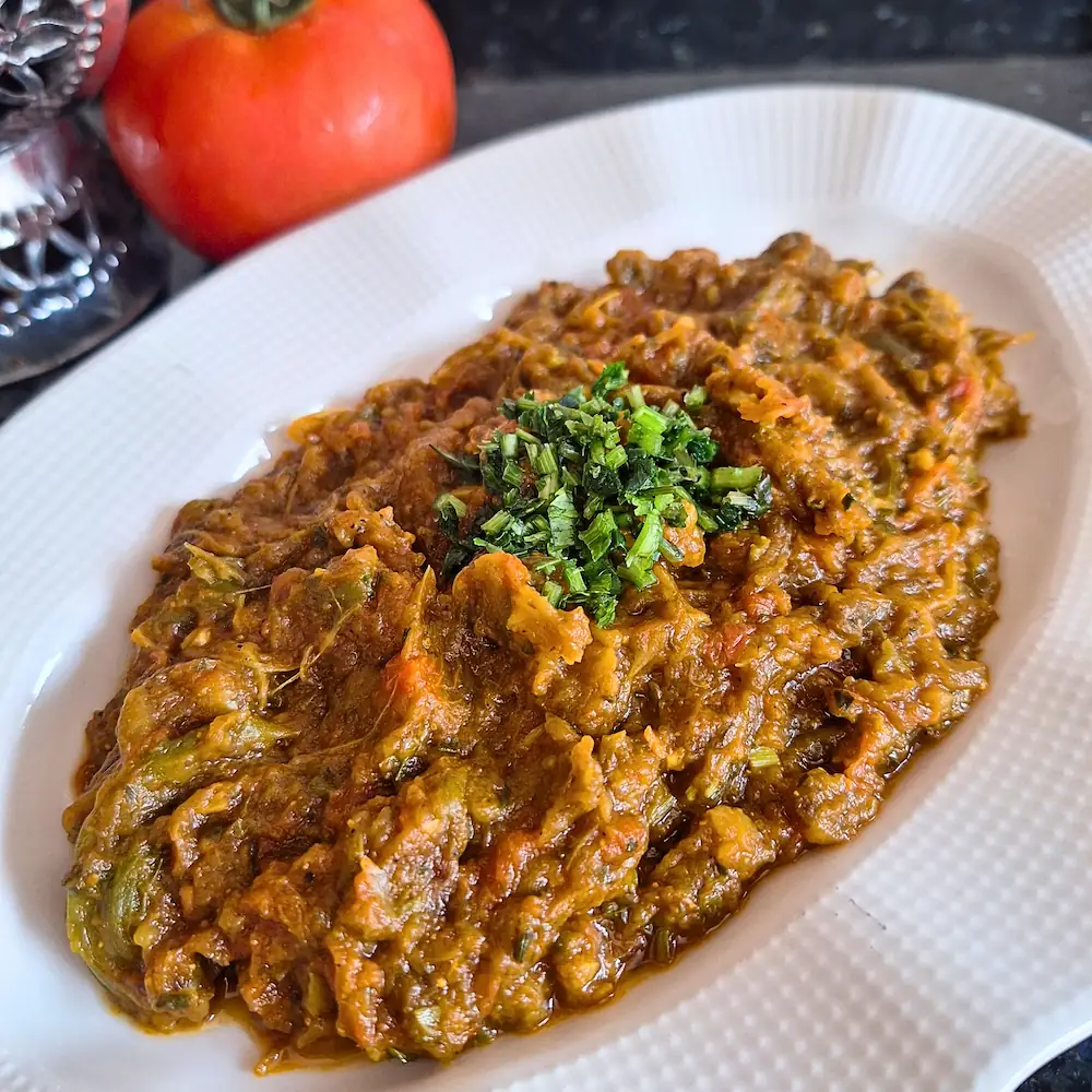 Close-up of a savory, perfectly thick Moroccan eggplant dip served on a classic white plate, ready to be scooped up with crusty bread.